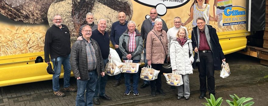 Mitglieder des Radsportverein Bliesransbach stehen vor einem LKW der Bäckerei Gillen. Die Mitglieder haben gefüllte Papiertaschen der Bäckerei Gillen in der Hand